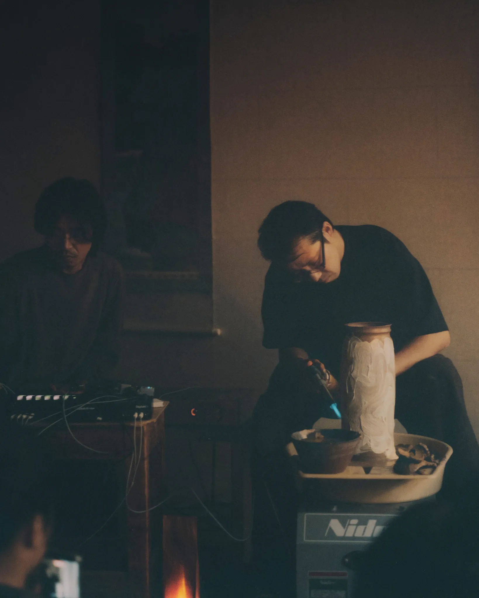 Hands on a sampler, and Huh Namhoon performing while Tōsei throws a tall vessel on the wheel
