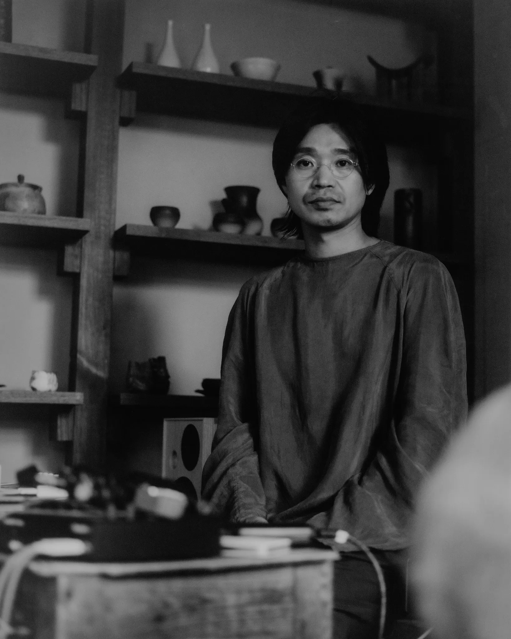 A freshly thrown vessel resting on the wheel, and a portrait in the studio