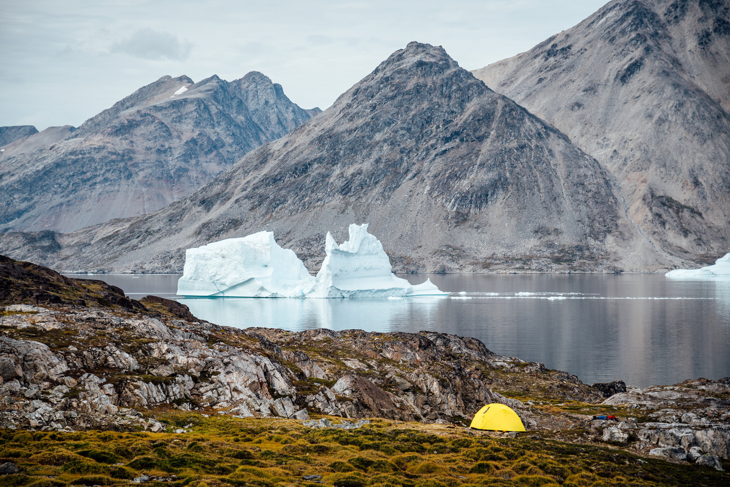A tent site with an iceberg in the background, Between Kulusuk and Kuummiut. Photo - Chris B. Lee, Visit Greenland
